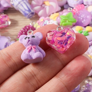 Close-up of cute purple resin bear and pink glitter heart charms for DIY jewelry making