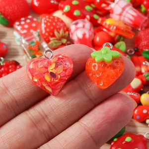 Macro shot of resin strawberry and heart pendants with silver rings for DIY crafts