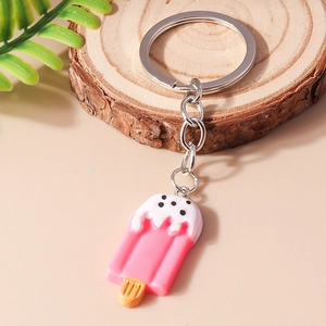 Close-up of pink ice cream keychain with white melting cream detail on wooden base