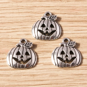 Three antique silver Halloween pumpkin charms on wood background for DIY jewelry