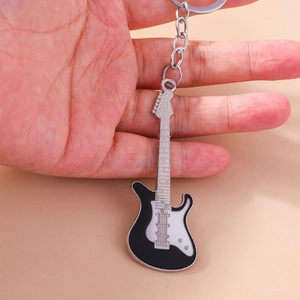 Detailed close-up of a stylish black and white electric guitar keychain held by hand