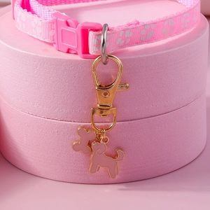 Pink dog collar detail with paw prints, bone and poodle charms on a golden metal ring