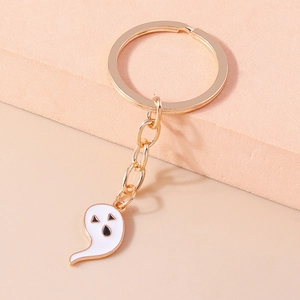 Close-up of golden keychain with cartoon ghost pendant and white enamel details
