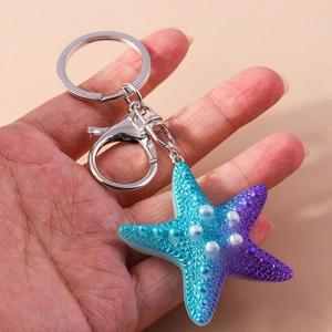 Detail of blue and purple gradient starfish keychain with white pearl bead accents