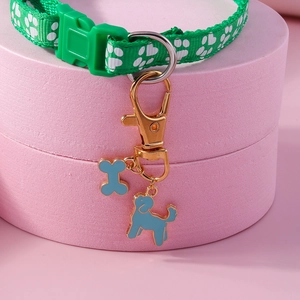 Detailed view of a green pet collar with white paw prints and blue enamel bone pendants