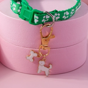 Close-up of green paw print collar with bone and dog charms on a pink background