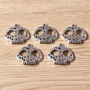 Detail view of five retro silver skull pendants with hollow carvings for DIY jewelry