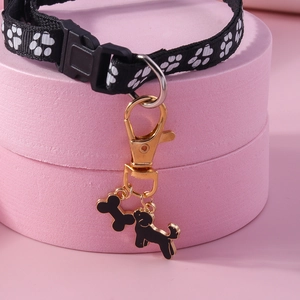 Close-up of a nylon dog collar with gold bone and poodle charms on pink stands