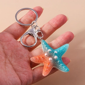 Creative resin starfish keychain with blue-orange gradient and pearl accents on hand