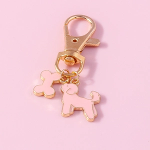 Close-up of golden lobster clasp with cute pink enamel dog and bone charms for keychains