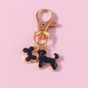 Macro detail of golden dog bone and poodle charms with black enamel on key ring