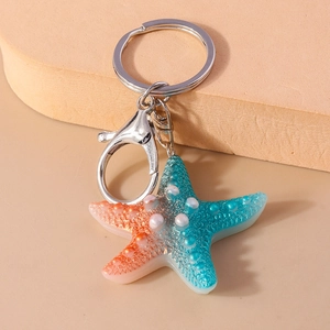 Macro detail of gradient resin starfish keychain with textured pearl dots and silver metal ring