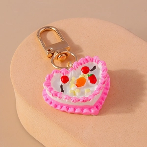 Detailed macro view of heart-shaped fruit cake keychain with pink cream and gold buckle