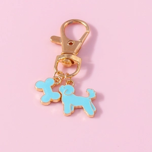 Close-up of a blue enamel dog and bone pendant on a golden metal keychain with pink background