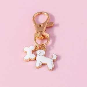 Detail of cute gold-edged dog and bone charms on a poodle keychain accessory