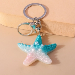 Detail of gradient resin starfish keychain with pearl beads on a display block