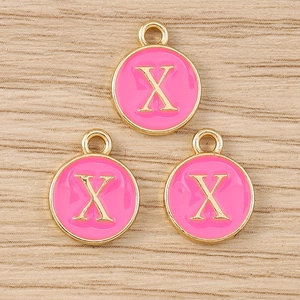 Close-up of pink enamel round letter X charms with gold metal edges for DIY jewelry making