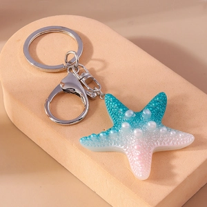 Detail view of a gradient resin starfish keychain with pearl texture and silver metal clasp