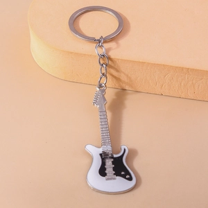 Detail view of electric guitar keychain with white face and black pickguard on metal alloy