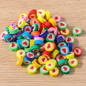 Bunte Perlen aus Fimo mit Herzmuster und gezackten Rändern auf Holzgrundlage