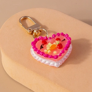 Detailed macro of heart-shaped cake keychain with cream texture and fruit inlay decorations
