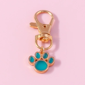 Cute gold cat paw pendant with teal enamel inlay and lobster clasp on pink background