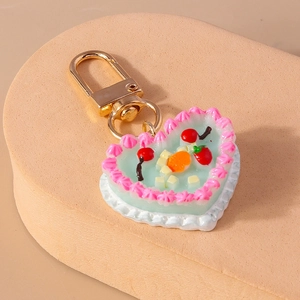 Detail of mint green heart cake keychain with strawberry and cream fruit decoration