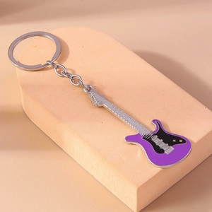 Close-up of a purple and black electric guitar keychain on a minimalist stand