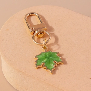 Detailed view of green enamel maple leaf keychain with golden metal ring and D-clasp