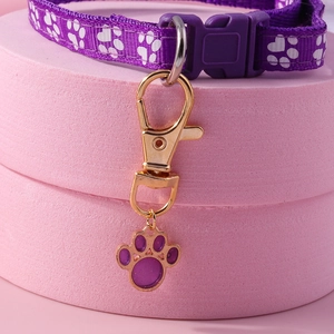 Close-up of purple nylon pet collar with white paw prints and golden charm pendant