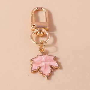 Detailed close-up of a pink enamel maple leaf pendant with gold lobster clasp for bags