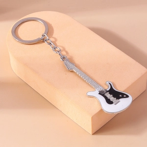 Detailed close-up of a black and white electric guitar keychain charm on a display block