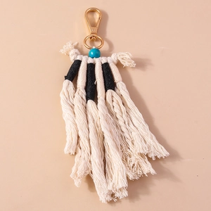 Dettaglio del portachiavi boho fatto a mano con nappa, perlina blu e chiusura dorata