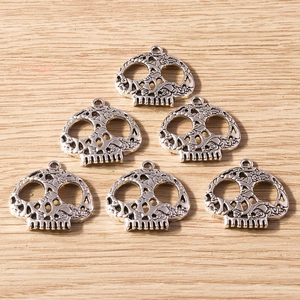 Detailed macro view of vintage silver skull charms with intricate hollow-out design for DIY jewelry