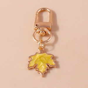 Detail view of a golden maple leaf keychain with yellow wavy texture and spring hook