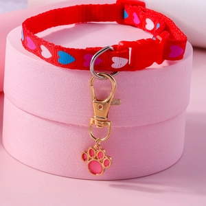 Detail of red pet collar with heart prints and a pink paw-shaped metal pendant