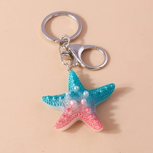 Close-up of blue pink gradient resin starfish keychain with pearls and silver lobster clasp