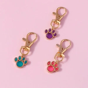 Three cute metal cat paw keychains in purple, green, and pink with gold lobster clasps