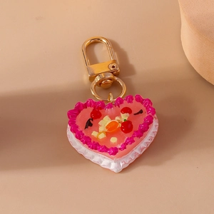 Macro view of heart cake keychain with cream frosting textures and fruit decorations