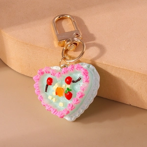 Detail of heart cake keychain with pink cream edges and tiny fruit toppings