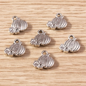 Detailed view of antique silver pumpkin charms for DIY jewelry on light wood surface