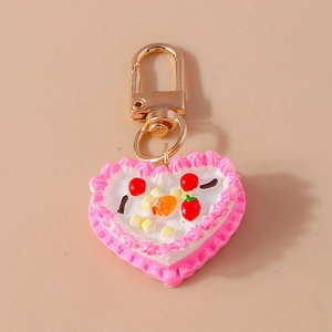Close-up of heart-shaped cake keychain with cream piping and miniature fruit details