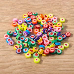 Flachbild von bunten Tonperlen mit Herzmuster und vorgebohrten Löchern für DIY-Schmuck