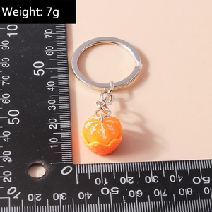 Detail of resin orange segment keychain with silver metal ring on a light background