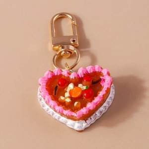 Detail of heart-shaped cake keychain with pink cream edges and golden metal clasp