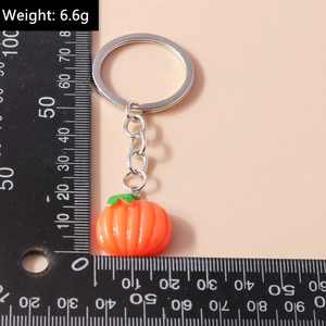 Realistic orange pumpkin keychain with green leaf showing weight and size on ruler