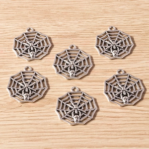 Macro detail of silver alloy spider web and skull pendants for DIY jewelry making