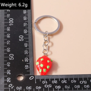 Detailed view of red strawberry keychain pendant with silver metal ring on scale