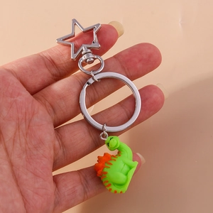 Cute green dinosaur keychain with orange spines and a silver star-shaped carabiner clip