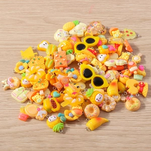 Close-up of assorted resin DIY pendants including pineapple, bear, and donut on wood